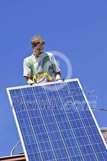 Man installing alternative energy photovoltaic solar panels on roof Man installing alternative energy photovoltaic solar panels on roof