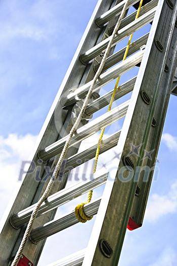 Closeup of construction aluminum extension ladder against blue sky