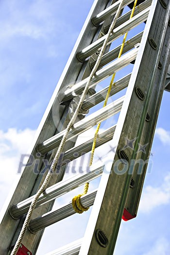 Closeup of construction aluminum extension ladder against blue sky Closeup of construction aluminum extension ladder against blue sky