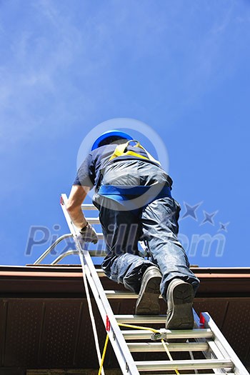 Construction worker climbing extension ladder to roof