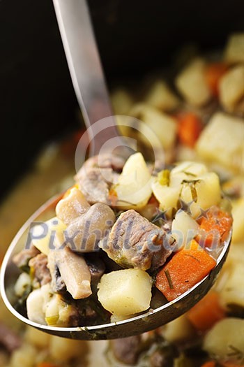 Hearty beef and potatoes stew with vegetables served with ladle Hearty beef and potatoes stew with vegetables served with ladle