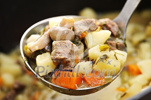 Hearty beef and potatoes stew with vegetables served with ladle Hearty beef and potatoes stew with vegetables served with ladle