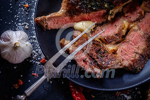 Entrecote with vegetables on dark plate close up.