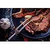 Entrecote with vegetables on dark plate close up.