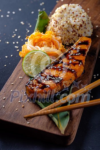 Teriyaki salmon with rice on a wooden platter.