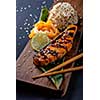 Teriyaki salmon with rice on a wooden platter.