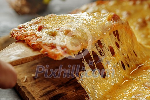 Pizza quattro fromaggi on a wooden board. Italian food. Man's hand takes a slice of fresh delicious pizza. Pizza quattro fromaggi on a wooden board. Italian food. Man's hand takes a slice of fresh delicious pizza.