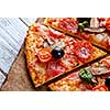 Delicious fresh pizza with mushrooms, cherry and pepperoni served on wooden table. Close-up slice tasty pizza. Mediterranean cuisine.