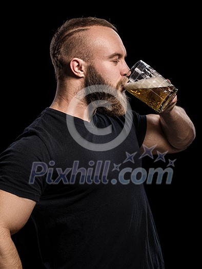 Bearded man drinking beer from a beer mug over black background Bearded man drinking beer from a beer mug over black background