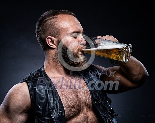 Bearded man drinking beer from a beer mug over grunge background Bearded man drinking beer from a beer mug over grunge background
