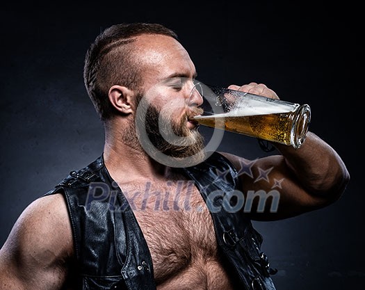 Bearded man drinking beer from a beer mug over grunge background