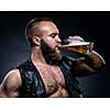 Bearded man drinking beer from a beer mug over grunge background