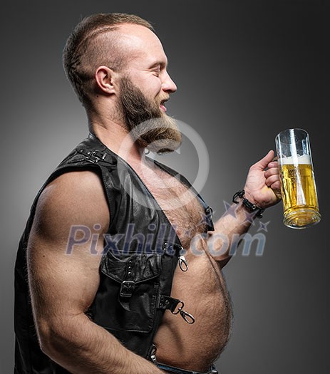 Smiling biker with beer belly. Man drinks beer from a mug.