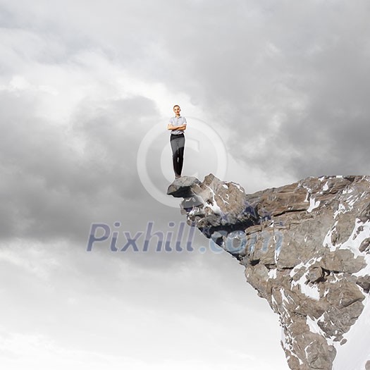 Risky businesswoman standing on edge of rock Risky businesswoman standing on edge of rock