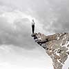 Risky businesswoman standing on edge of rock