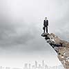 Young businessman standing on edge of rock mountain