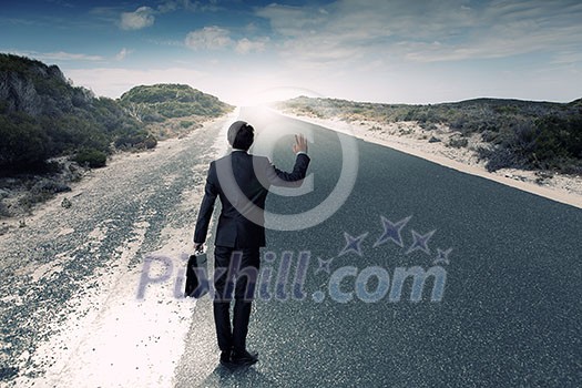 Back view of businessman standing on road and looking far away Back view of businessman standing on road and looking far away