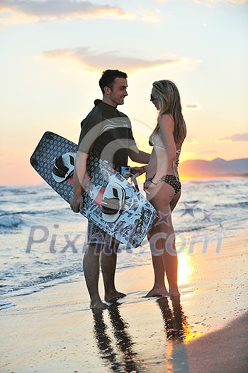 romantic couple in surf wear posing at beach on sunset at summer season romantic couple in surf wear posing at beach on sunset at summer season