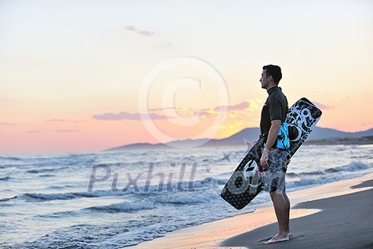 Portrait of a strong young surf man at beach on sunset in a contemplative mood with a surfboard Portrait of a strong young surf man at beach on sunset in a contemplative mood with a surfboard