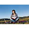 young teen girl read book and study homework outdoor in nature with blue sky in background