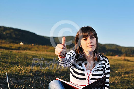 young teen girl read book and study homework outdoor in nature with blue sky in background