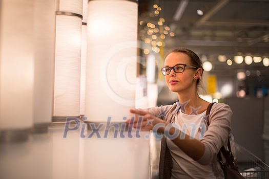 Pretty, young woman choosing the right light for her appartment in a modern home furnishings store (color toned image; shallow DOF) Pretty, young woman choosing the right light for her appartment in a modern home furnishings store (color toned image; shallow DOF)
