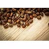 Coffee beans on a wooden desk lit by warm light (shallow DOF; color toned image)