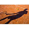 Shadow of a tennis player in action on a tennis court (conceptual image with a tennis ball lying on the court and the shadow of the player positioned in a way he seems to be playing it)