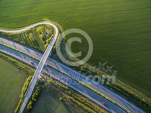 Aerial view of a highway amid fields with cars on it Aerial view of a highway amid fields with cars on it