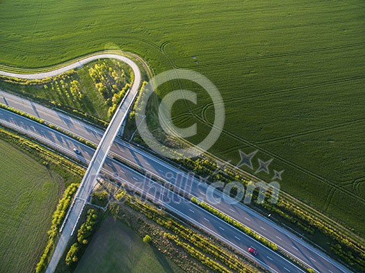 Aerial view of a highway amid fields with cars on it