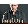 Man looking at wooden chess board thinking about first move