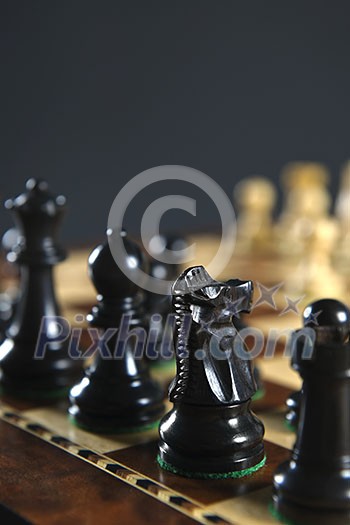 Close up of black chess pieces on wooden chessboard Close up of black chess pieces on wooden chessboard