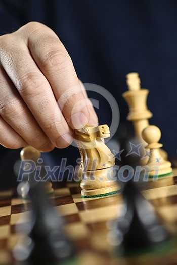 Hand moving a knight chess piece on wooden chessboard
