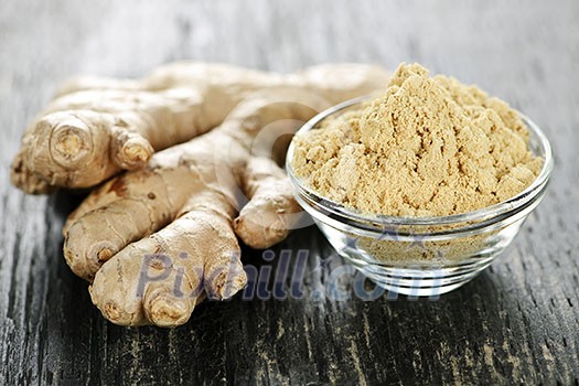 Fresh and ground ginger root spice on wooden table Fresh and ground ginger root spice on wooden table