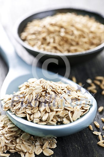 Rolled oats heaped on a spoon and whole oat groats Rolled oats heaped on a spoon and whole oat groats