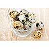 Many small brown spotted quail eggs in bowl