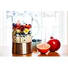 Healthy smoothie ingredients in blender with fresh fruit ready to blend on kitchen table