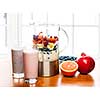 Prepared smoothies and healthy smoothie ingredients in blender with fresh fruit ready to blend on kitchen table