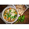 Chicken rice soup with vegetables in bowl and bread from above