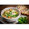 Chicken rice soup with vegetables in bowl and bread on rustic table