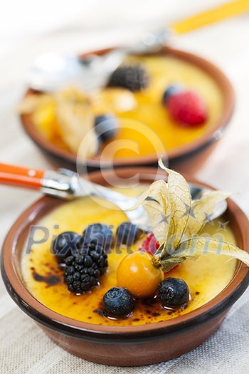 Sweet creme brulee desserts topped with fresh berries Sweet creme brulee desserts topped with fresh berries