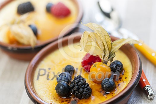 Sweet creme brulee desserts topped with fresh berries Sweet creme brulee desserts topped with fresh berries
