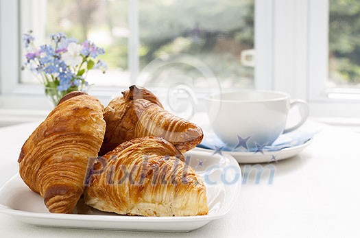 Three fresh baked croissants on plate for breakfast