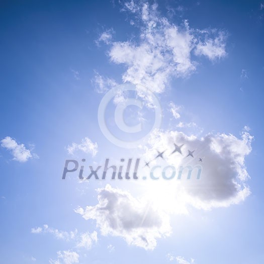 Square blue sky background with bright sun flare shining through clouds Square blue sky background with bright sun flare shining through clouds