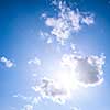 Square blue sky background with bright sun flare shining through clouds