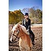 Portrait of teenage girl riding horse outdoors on sunny autumn day