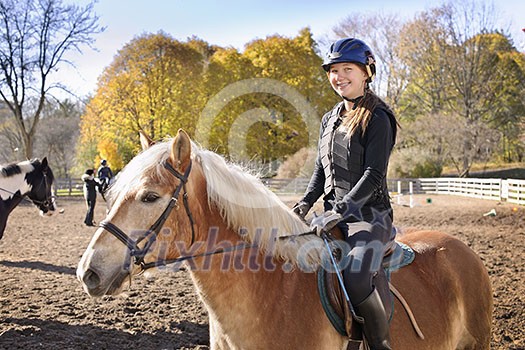 Portrait of teenage girl riding horse outdoors on sunny autumn day