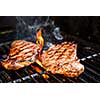 Beef steaks cooking in open flame on barbecue grill