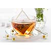 Glass teacup with soothing herbal tea in silk bag