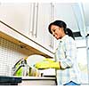 Smiling young black woman washing dishes in kitchen